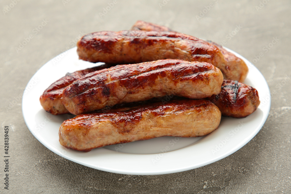Grilled sausages on white plate on grey background Grilled sausages on white plate on grey background