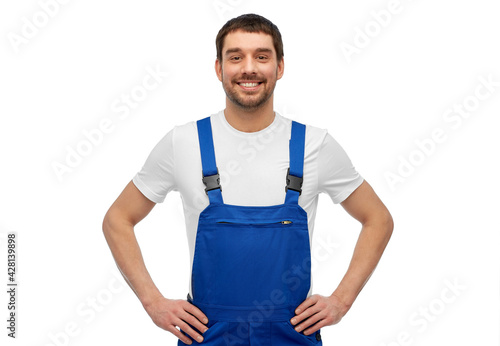 profession, construction and building concept - happy smiling male worker or builder in overall over grey background