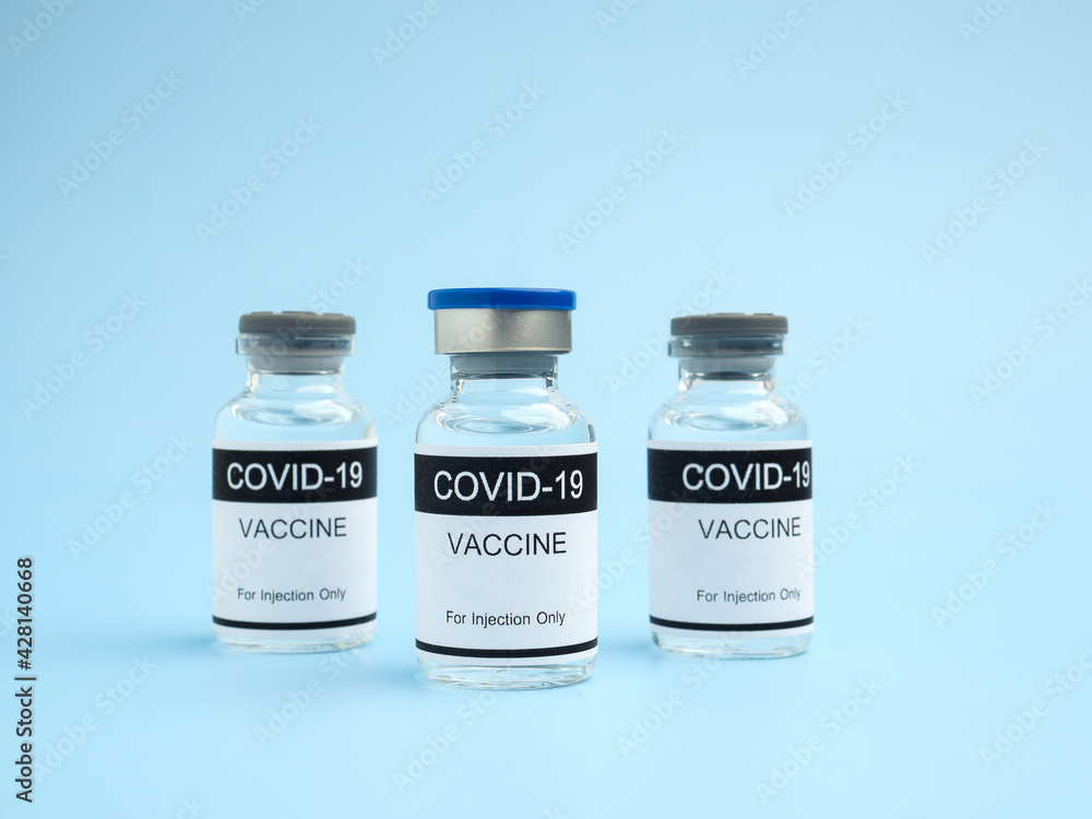 COVID-19 vaccine in glass bottles placed on a light blue background. Vaccine for immunization, and treatment from coronavirus infection. Side view. Close-up photo. Concept of medical and healthcare COVID-19 vaccine in glass bottles placed on a light blue background. Vaccine for immunization, and treatment from coronavirus infection. Side view. Close-up photo. Concept of medical and healthcare