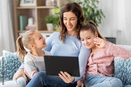 people, family and technology concept - happy mother and two daughters with tablet pc computer having video call at home