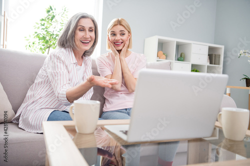 Photo of happy excited cheerful mom and daughter sit couch look laptop movie indoors inside house home © deagreez
