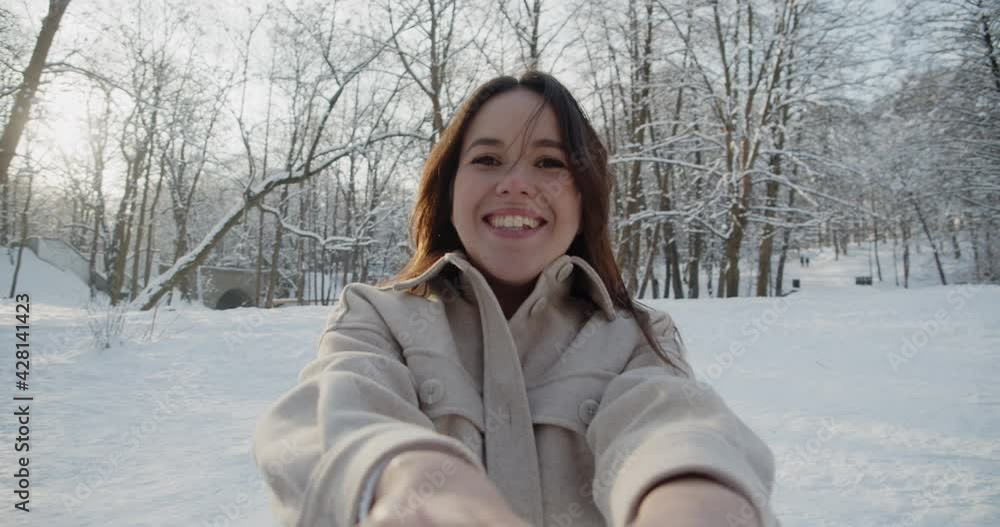 Happy young beautiful couple have fun in sunny winter forest together. Man and woman circle around holding hands laughing. Close-up portrait of a young woman. Slow motion. Happy young beautiful couple have fun in sunny winter forest together. Man and woman circle around holding hands laughing. Close-up portrait of a young woman. Slow motion.