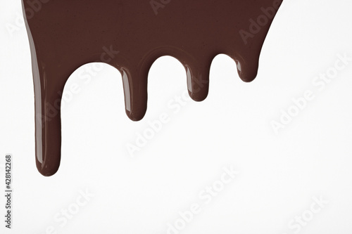 Dark chocolate liquid drops of paint flow down on isolated white background. Abstract brown color backdrop
