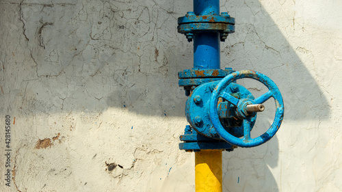 blue gas valve wire on the background of a cracked wall