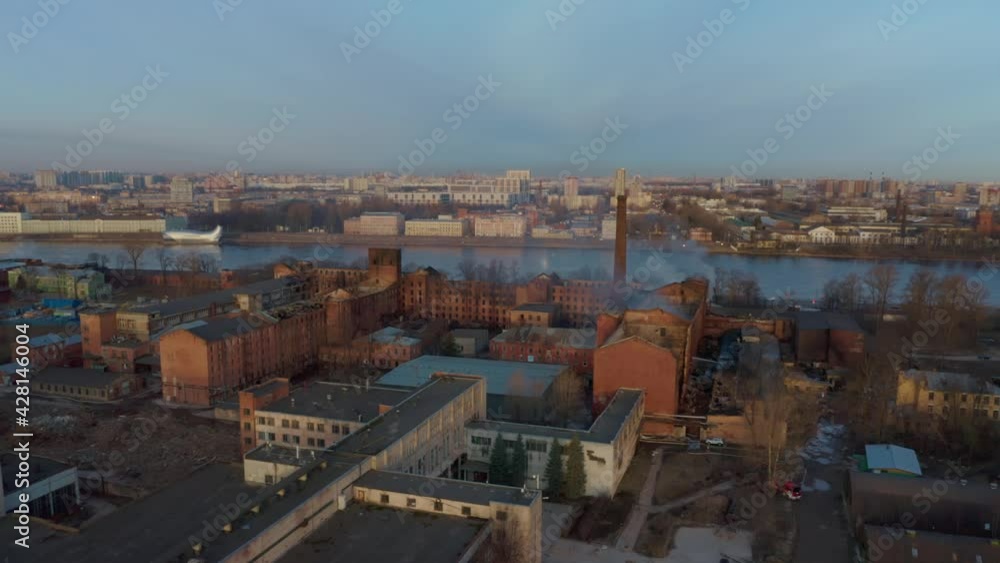 A large factory on the banks of the river after a fire. Ruined walls, smoke coming. Firefighters extinguish the remnants of the fire. Taken from a drone. A large factory on the banks of the river after a fire. Ruined walls, smoke coming. Firefighters extinguish the remnants of the fire. Taken from a drone.