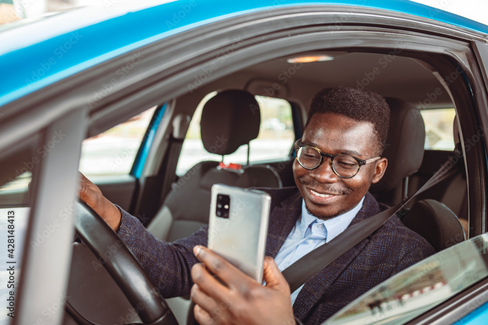 Cropped shot of a man using his phone while driving. Business texting. Businessman using mobile phone in the car. Man looking at mobile phone while driving a car.