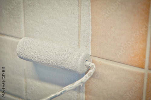 Painting old tiles in the kitchen or bathroom white with a small roller and two component paint. © Kristof