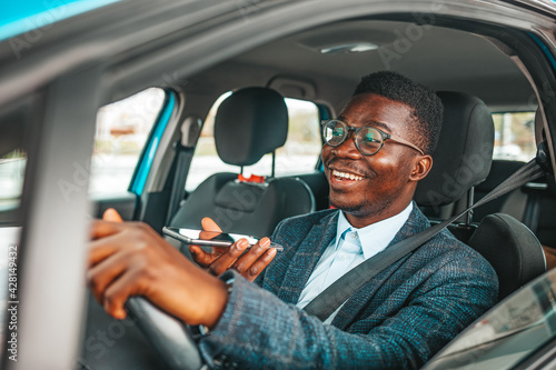 Man talking on the smartphone and driving a car. Successful Man Sitting Behind the Wheel of a Prestigious Car and Talking to his Client on the Phone.