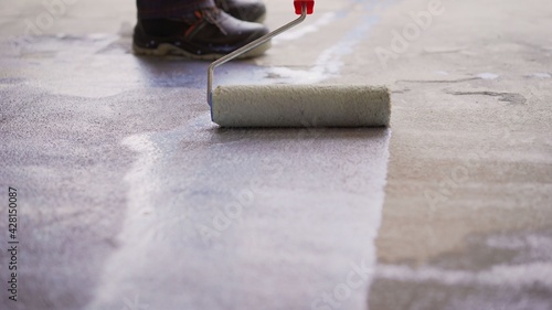 Priming Concrete floor before laying tiles on it, the final preparatory stage for strengthening the surface. Floor priming process.