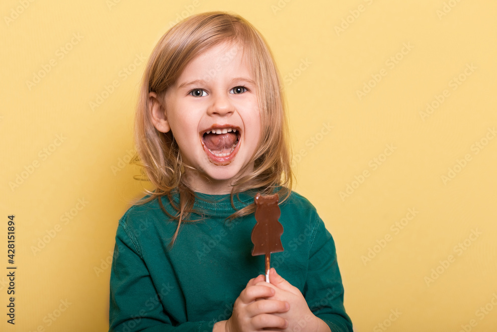 Little girl smiling and holding a chocolate bunny on a yellow background Little girl smiling and holding a chocolate bunny on a yellow background