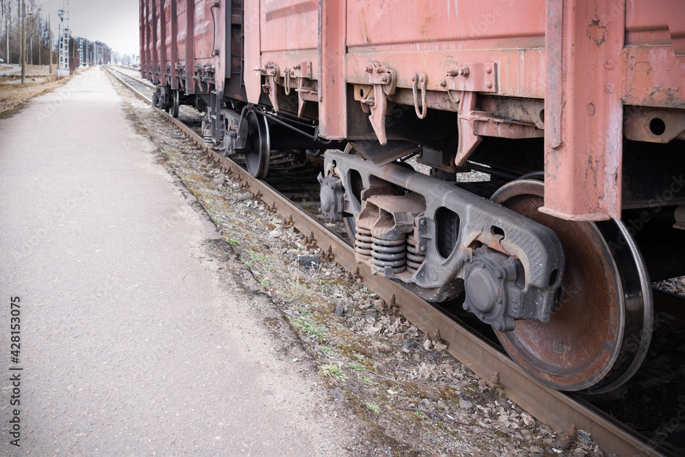 Naklejka premium Train wheels on rails, lower part of carriages, asphalt road.