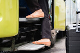 close up of the feet of a woman in shoes stepping up the bus door steps before leaving by bus