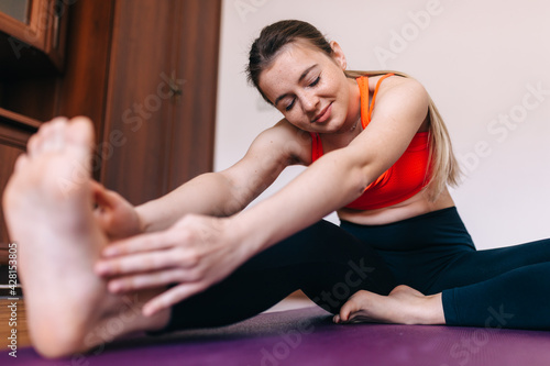 A young girl does yoga in a bright room. Training and healthy lifestyle.