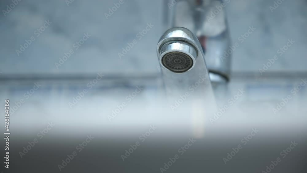 Dripping old faucet in bathroom. Water dripping from a tap into white sink, close-up bottomview. Reckless use of resources. Broken plumbing. Dripping old faucet in bathroom. Water dripping from a tap into white sink, close-up bottomview. Reckless use of resources. Broken plumbing.