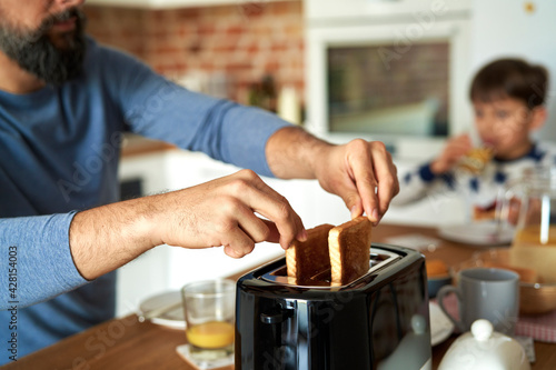 Photos Close up of man pulling toast from a toaster