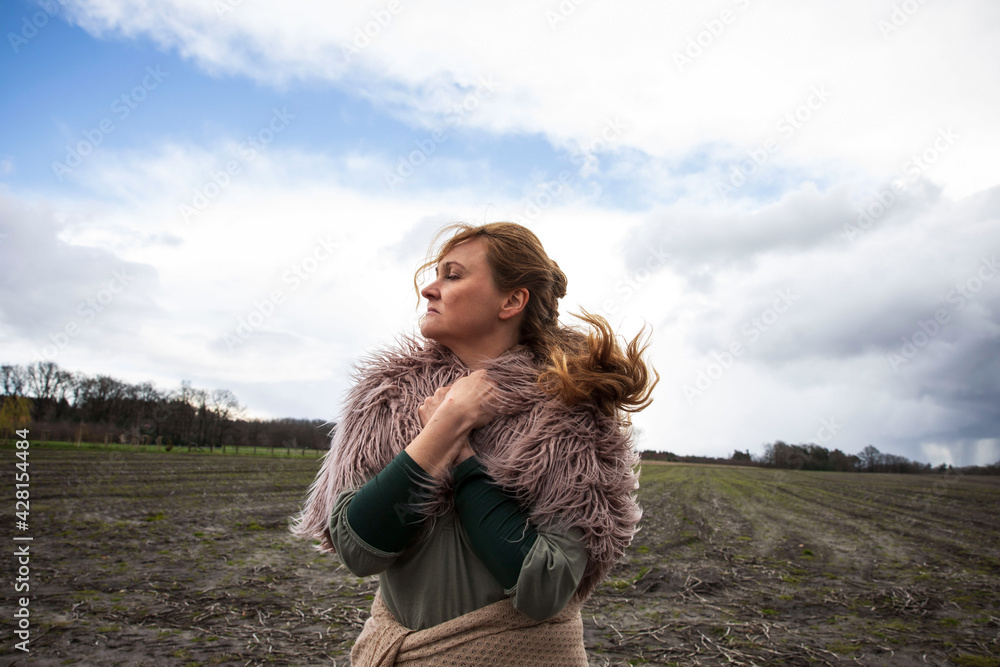 Arme Frau im mittelalter geht auf dem Feld, hat Fell auf den Schultern an. Die Hände liegen auf den Schultern, sie schaut zur Seite, es ist windig und sie sieht traurig und sehnsüchtig aus. Arme Frau im mittelalter geht auf dem Feld, hat Fell auf den Schultern an. Die Hände liegen auf den Schultern, sie schaut zur Seite, es ist windig und sie sieht traurig und sehnsüchtig aus.