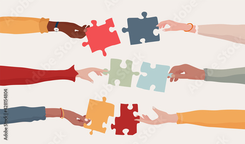 Cooperation and collaboration concept. Hands holding a jigsaw puzzle piece which joins another puzzle piece. Communication between diverse people. Arms of multiethnic people. Team. Banner
