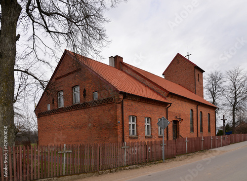Fototapeta Naklejka Na Ścianę i Meble -  Built in the neo-Gothic style of red ceramic brick in 1921, the Catholic Church of St. Andrew the Apostle in the village of Prawdziska in Masuria, Poland. The photos show a general view of the temple.