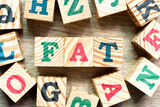 Alphabet letter block in word FAT (Obesity or abbreviation of factory acceptance test, file allocation table) with another on wood background