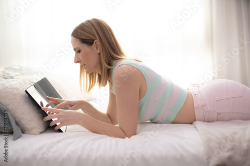 Beautiful woman lying on the bed reading a book