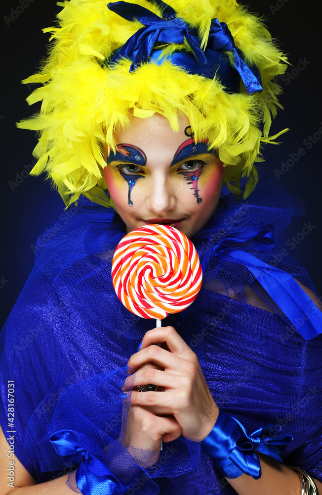 Young woman with creative visage with lollipop. Party and carnival. Bright wig.