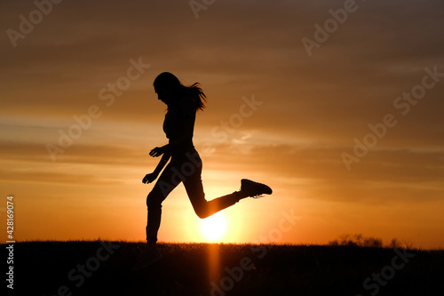 Woman silhouette jump at sunset background at summer.