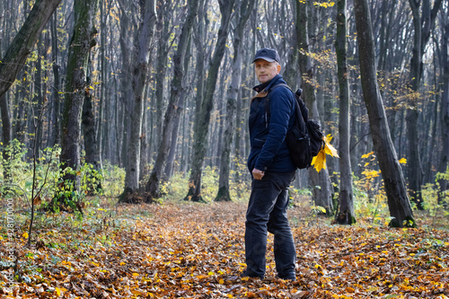 Man with a backpack in the autumn forest. A walk in the autumn forest. Unity with nature