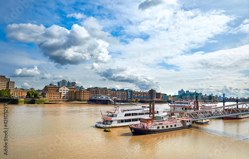 River Thames in East London on a bright sunny day with passenger boats on the foreground. Wappping and St. Katharine's Docks are on the other shore. photo