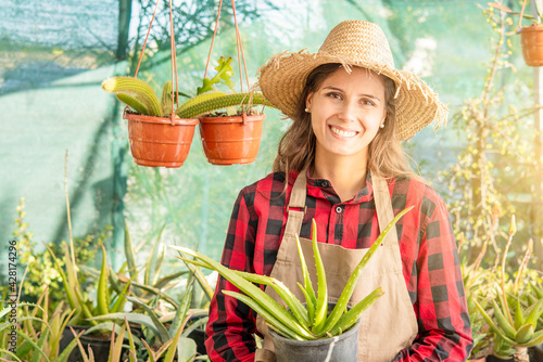 smiling woman in a plant nursery with an aloe plant in her hand green hobby