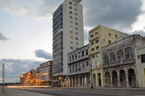 Long exposure dawn scene in Havana at the Malecon seaside avenue. Decay buildings at sunrise with skyscraper in street in Cuba traffic trail lights. Morning scene with empty street.