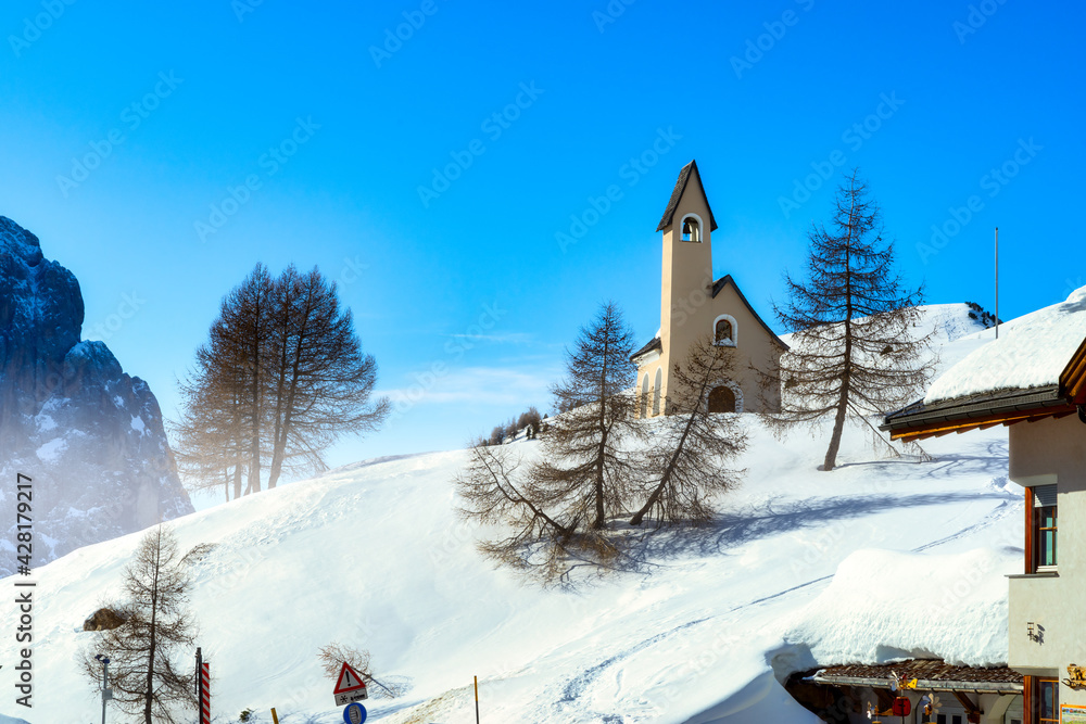 Wolkenstein in Gröden in winter with chapel and view to the pizes de cir, Dolomite, Italy