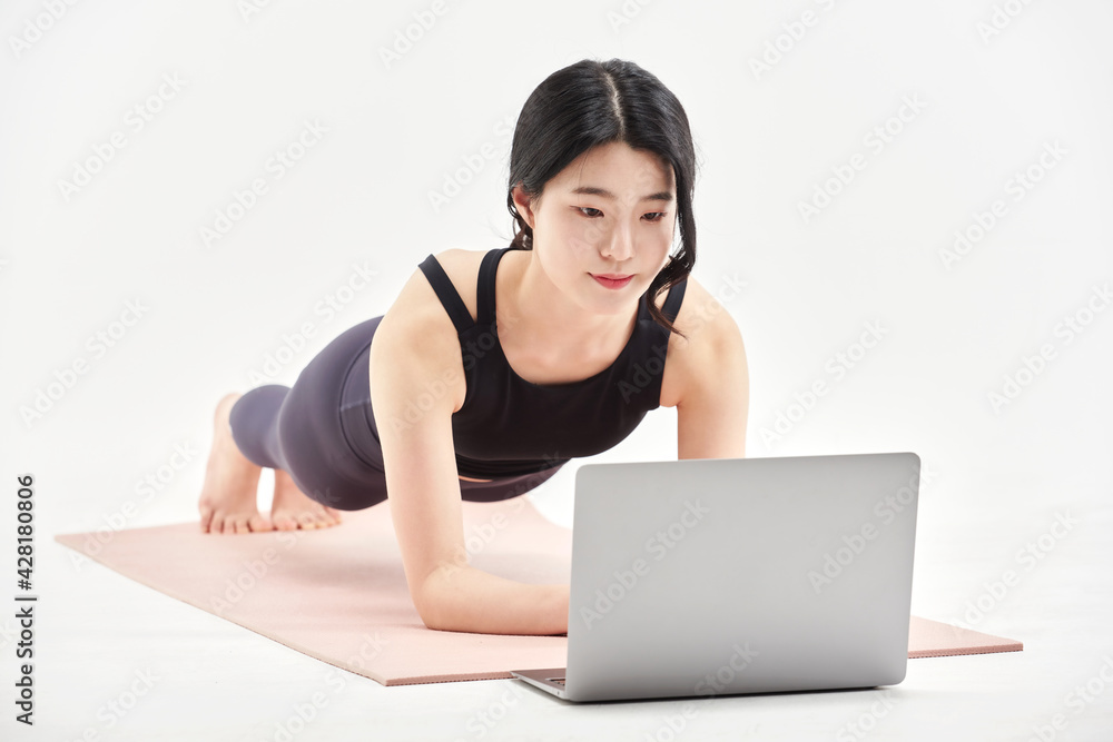 Asia korean girl long haired beautiful pilates or yoga athlete does a graceful pose while wearing a tight sports outfit against a white background in a studio Asia korean girl long haired beautiful pilates or yoga athlete does a graceful pose while wearing a tight sports outfit against a white background in a studio