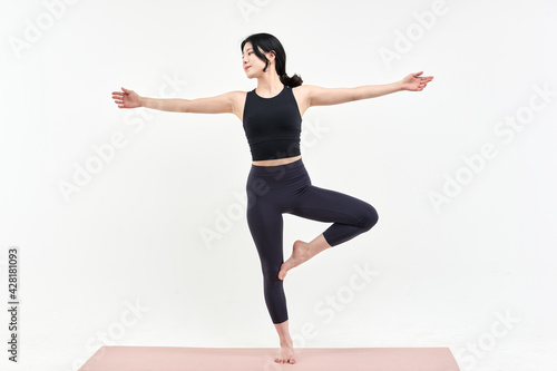 Asia korean girl long haired beautiful pilates or yoga athlete does a graceful pose while wearing a tight sports outfit against a white background in a studio © TEAM PRE-LIGHT