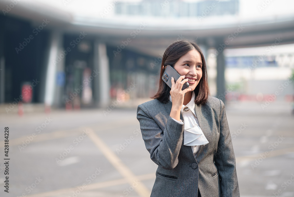 Portrait of young beautiful Asian business woman wear formal suit looking away while talking on smart phone technology. Successful assistance manager career have professional lifestyle in modern city. Portrait of young beautiful Asian business woman wear formal suit looking away while talking on smart phone technology. Successful assistance manager career have professional lifestyle in modern city.
