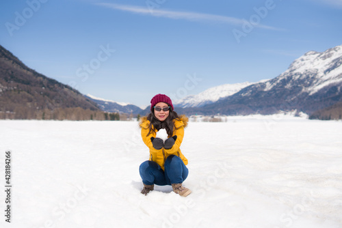 winter holidays - young happy and attractive Asian Japanese woman enjoying playful on snow at beautiful Swiss Alps landscape during Christmas vacation trip