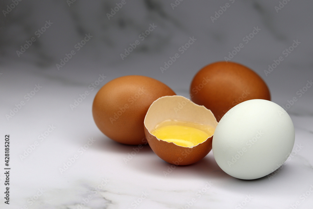 Chicken eggs of different colors and one broken with the yolk inside Chicken eggs of different colors and one broken with the yolk inside