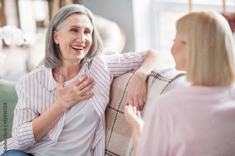 Photo of positive old lady young woman smile hold hand chin speak good mood indoors inside house home