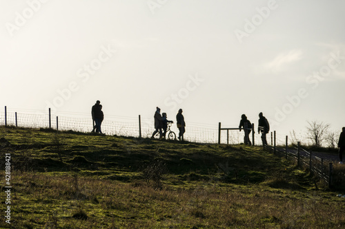 Silhouette of people walking with child on bike in country park on cold day
