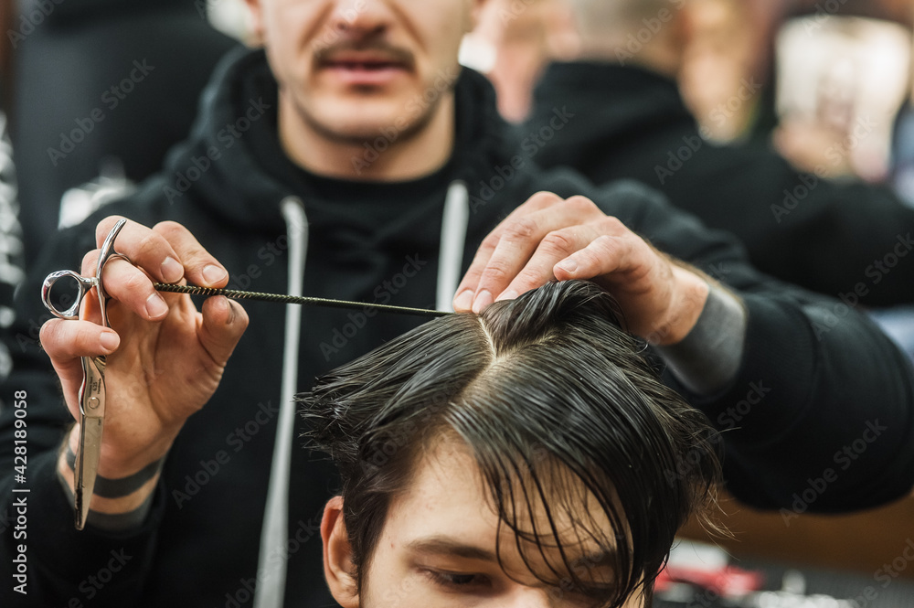 Naklejka premium Hipster client man visiting in barber shop shaving hair. Modern guy having his hair cut in barbershop.