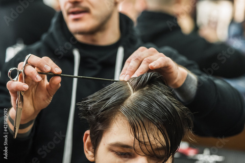 Hipster client man visiting in barber shop shaving hair. Modern guy having his hair cut in barbershop.