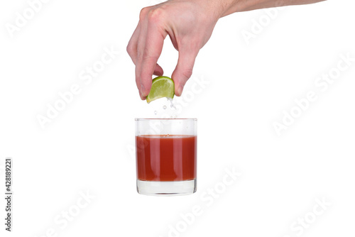Lime is squeezed into a glass of tomato juice.