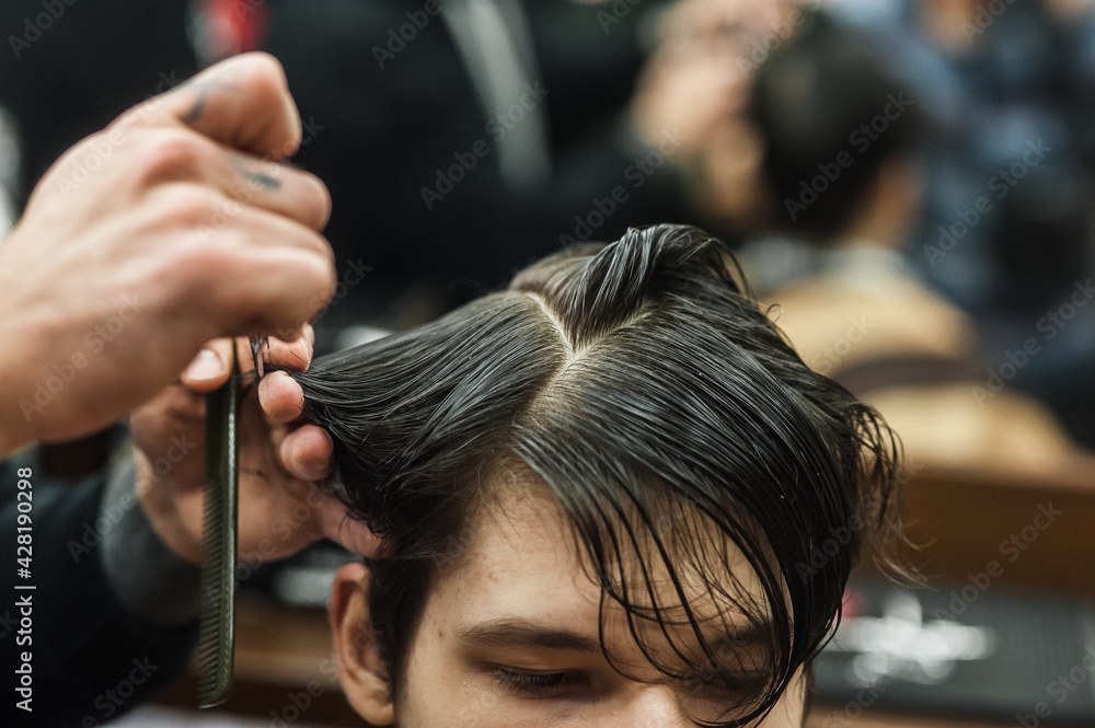 A man in a barbershop.Modern guy having his hair cut in barbershop A man in a barbershop.Modern guy having his hair cut in barbershop