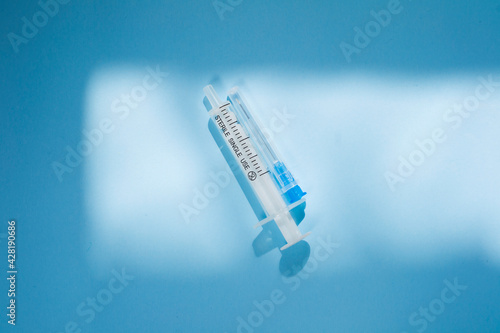 Injection syringe on a blue background. Health care essential equipment for injections.