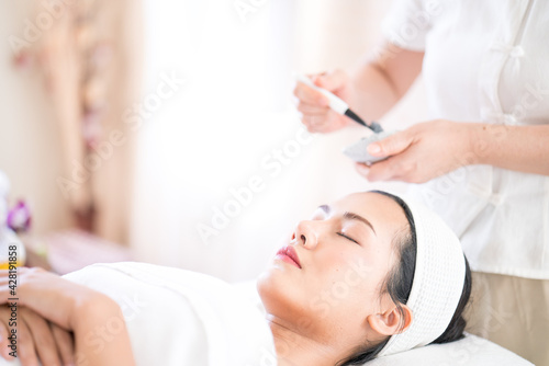 Beautiful woman masking skin in a facial spa shop.