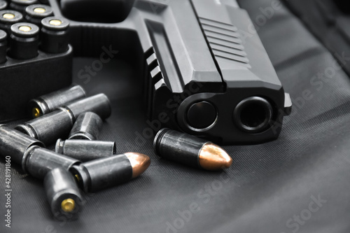 Automatic 9mm black pistol with bullets, bullet sheels on black background. photo