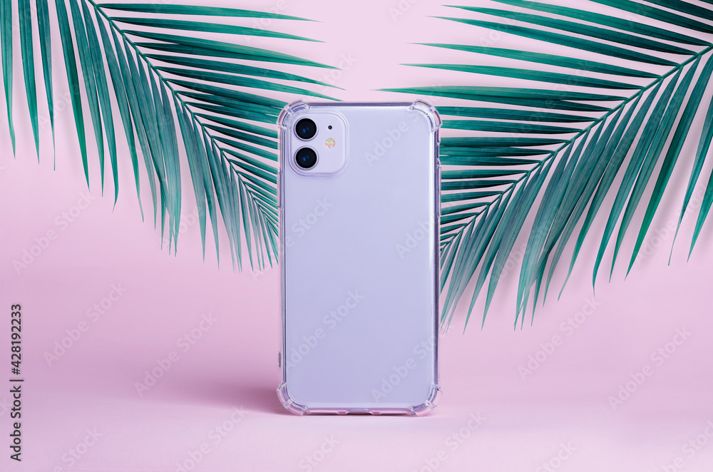 Stockfoto Purple iPhone 11 isolated on a pink background with palm