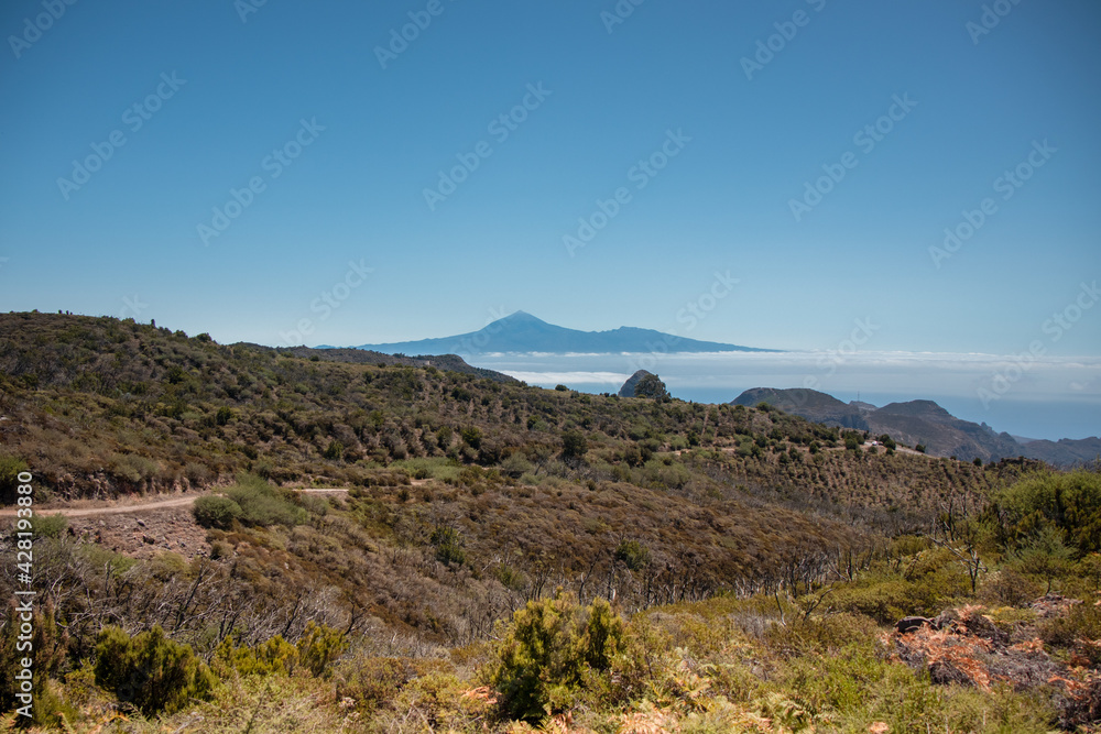 The landscape in the mountains leads to the ocean overlooking the neighbouring island and the volcano. A trip inland to the island of Gomera, Canary Islands. Travel on the paths of Garajonay National 