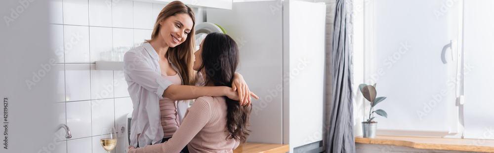 happy woman hugging girlfriend in kitchen, banner happy woman hugging girlfriend in kitchen, banner