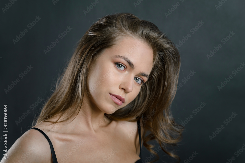 Fototapeta premium portrait of a beautiful young girl with brown hair on a black background. attractive young woman blonde with blue eyes close up