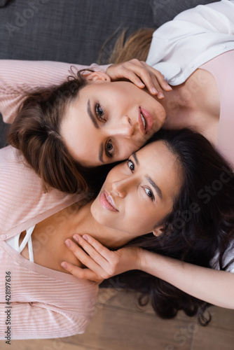 top view of positive lesbians hugging in living room
